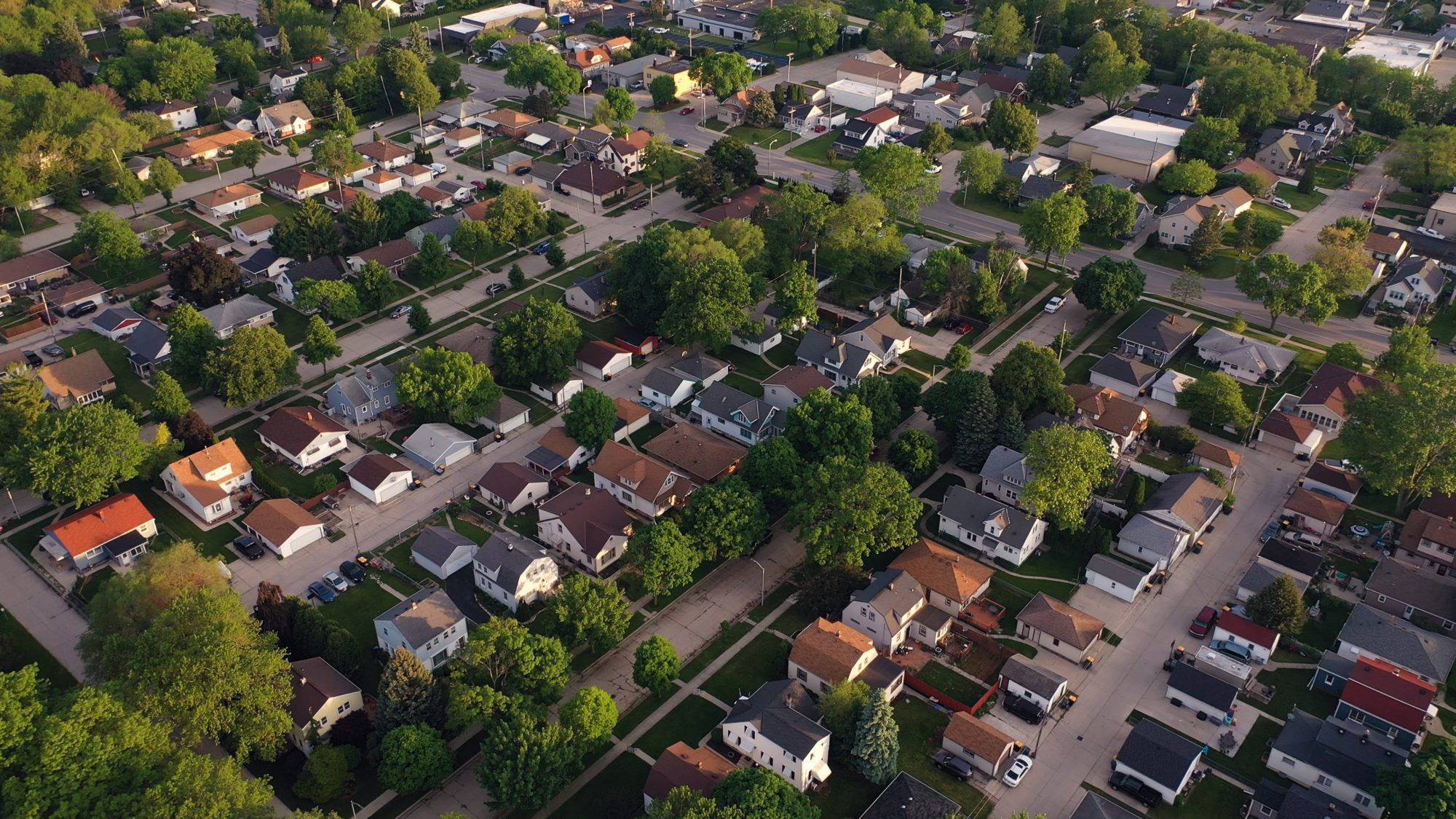 Aerial view of a suburban neighborhood with tree-lined streets, houses, and cross streets, capturing the charm of Hinsdale Wills community life.